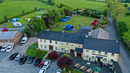Aerial photo of The Shepherds Rest Pub and Camping showing a lot of green field, building of the pub and some tents and caravans